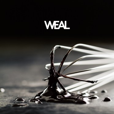 Beautiful metal baker whisk with chocolate on dark table on dark